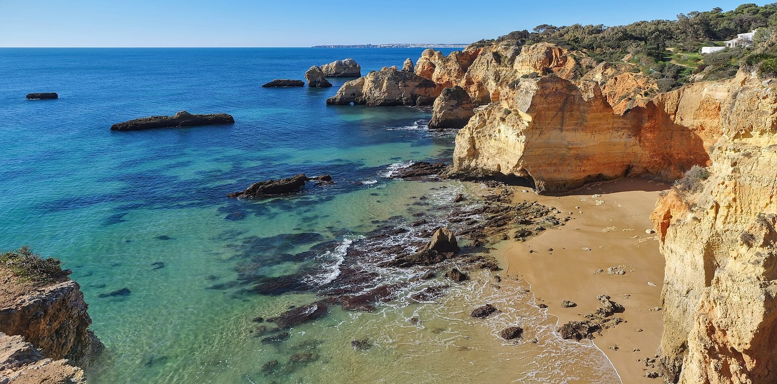 Les falaises dorées de l'Algarve au-dessus d'une plage et d'une eau claire