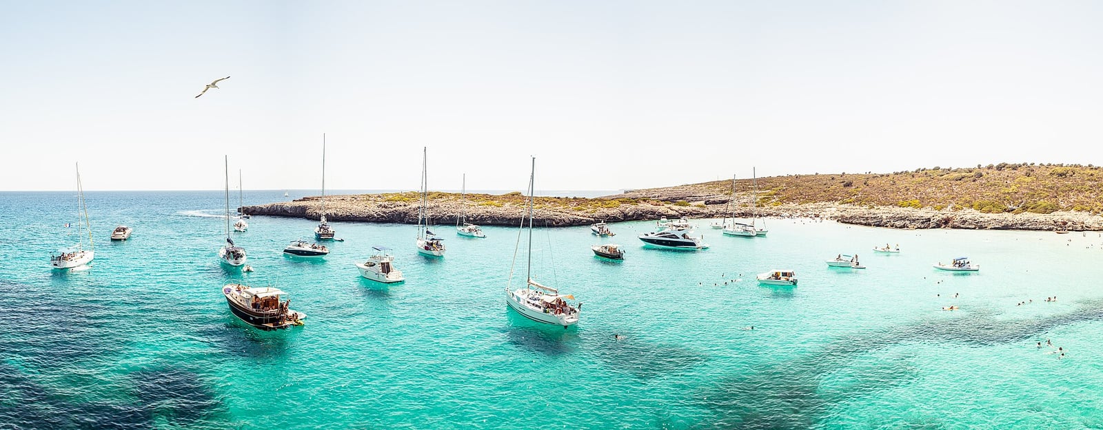 Une crique de Majorque à l'eau turquoise, des voiliers au mouillage devant la côte rocheuse